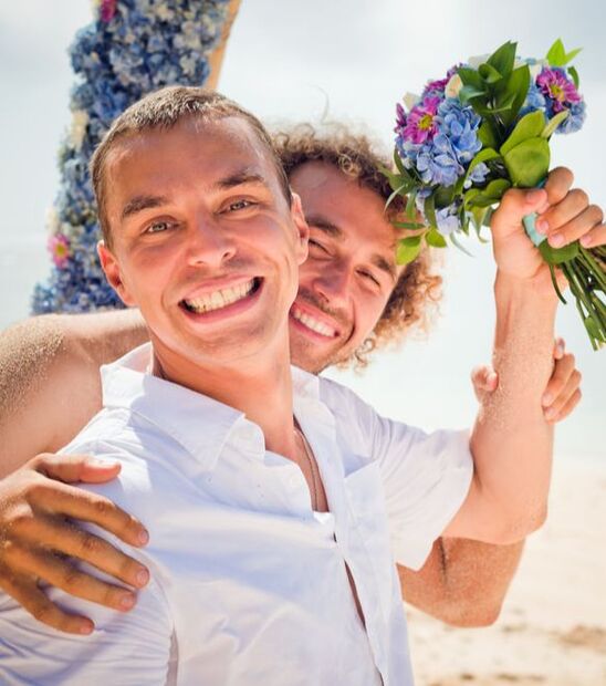 grooms on beach with flowers