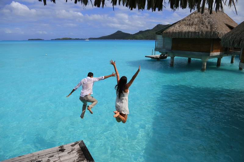 couple jumping in water at resort
